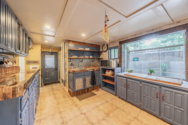 2057 Breezywood Dr, Flower Mound, TX 75022 - kitchen with gray cabinetry, open shelves, stone countertops, tasteful backsplash, and stainless steel microwave