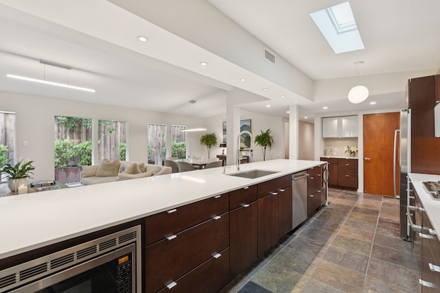 10832 Cinderella Ln, Dallas, TX 75229 - kitchen featuring appliances with stainless steel finishes, a skylight, light countertops, hanging light fixtures, and open floor plan
