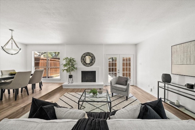 9206 Flickering Shadow Dr, Dallas, TX 75243 - living area featuring wood finished floors, french doors, a textured ceiling, and a fireplace with raised hearth
