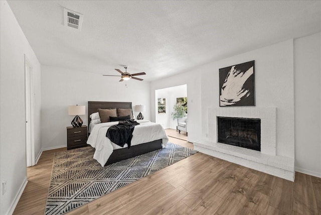 9206 Flickering Shadow Dr, Dallas, TX 75243 - bedroom with wood finished floors, a brick fireplace, and ceiling fan