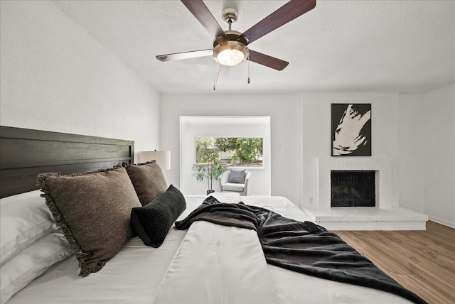 9206 Flickering Shadow Dr, Dallas, TX 75243 - bedroom with wood finished floors, a fireplace, a textured ceiling, and a ceiling fan