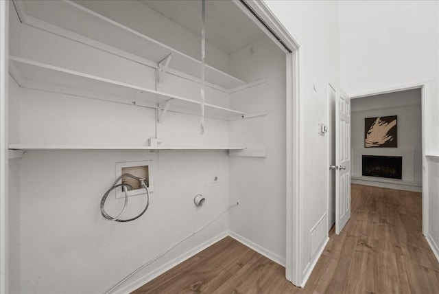 9206 Flickering Shadow Dr, Dallas, TX 75243 - laundry area with electric dryer hookup, wood finished floors, washer hookup, a fireplace with raised hearth, and gas dryer hookup