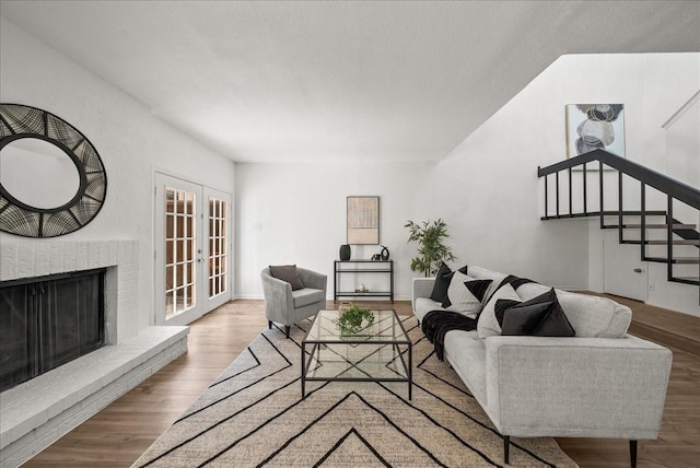 9206 Flickering Shadow Dr, Dallas, TX 75243 - living room featuring french doors, stairway, wood finished floors, a fireplace, and a textured ceiling