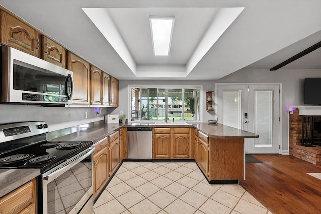 4201 Blackwillow Dr, Mesquite, TX 75150 - kitchen with appliances with stainless steel finishes, a peninsula, a tray ceiling, light tile patterned floors, and dark countertops