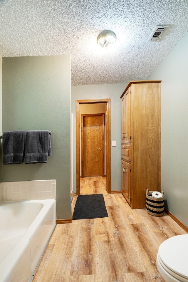 730 Cedar Crk, Reno, TX 75462 - full bathroom with a garden tub, wood finished floors, a textured ceiling, and a stall shower