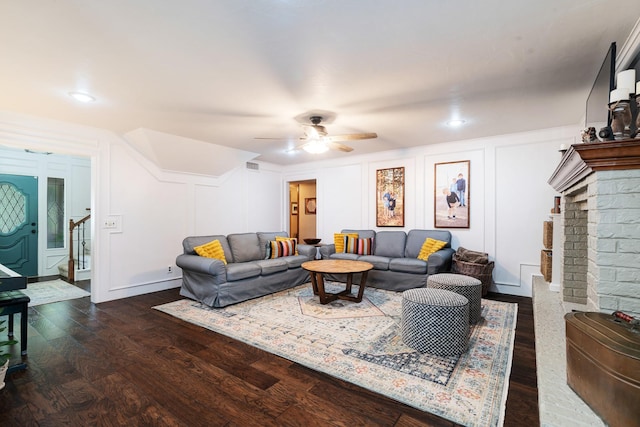 730 Cedar Crk, Reno, TX 75462 - living area with stairs, dark wood-style floors, a ceiling fan, a brick fireplace, and a decorative wall
