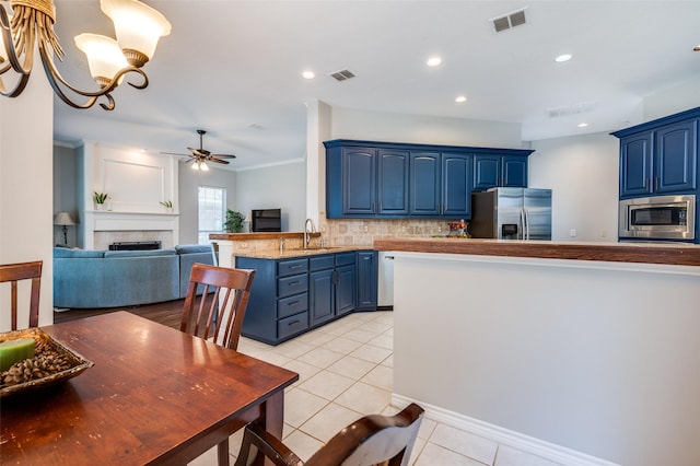 214 Chisholm Trl, Argyle, TX 76226 - kitchen with stainless steel appliances, blue cabinets, light tile patterned flooring, a peninsula, and recessed lighting