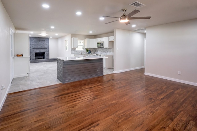820 Vickie Dr, Azle, TX 76020 - kitchen featuring stainless steel microwave, open floor plan, a fireplace, ceiling fan, and white cabinetry