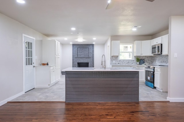 820 Vickie Dr, Azle, TX 76020 - kitchen with stainless steel appliances, a large fireplace, white cabinets, light wood-type flooring, and recessed lighting