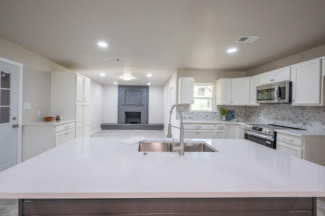 820 Vickie Dr, Azle, TX 76020 - kitchen featuring appliances with stainless steel finishes, white cabinets, a center island with sink, tasteful backsplash, and recessed lighting