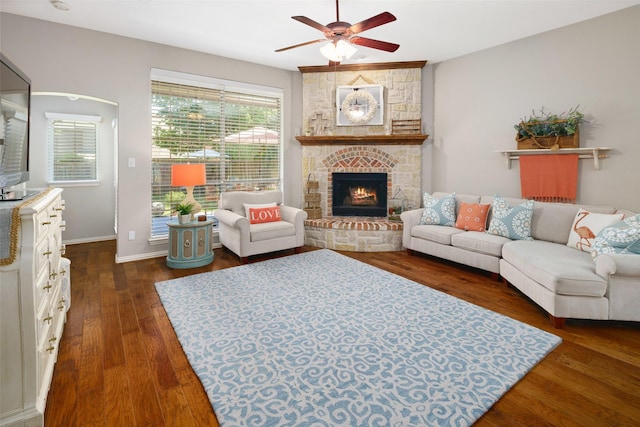 7716 Glenwood Springs Ln, Mckinney, TX 75070 - living room featuring a ceiling fan, a stone fireplace, and dark wood-style floors