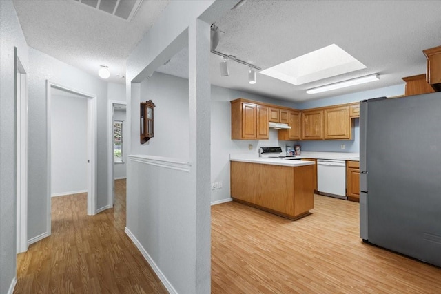 5521 Alta Verde Cir, Arlington, TX 76017 - kitchen with freestanding refrigerator, white dishwasher, a skylight, light wood-type flooring, and under cabinet range hood
