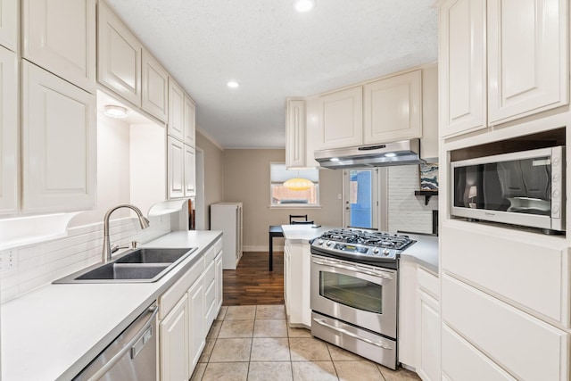 1432 Foothill Dr, Hurst, TX 76053 - kitchen featuring stainless steel appliances, under cabinet range hood, light countertops, recessed lighting, and washer / dryer