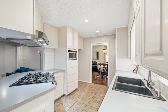 1432 Foothill Dr, Hurst, TX 76053 - kitchen featuring stainless steel microwave, cooktop, recessed lighting, light tile patterned floors, and light countertops