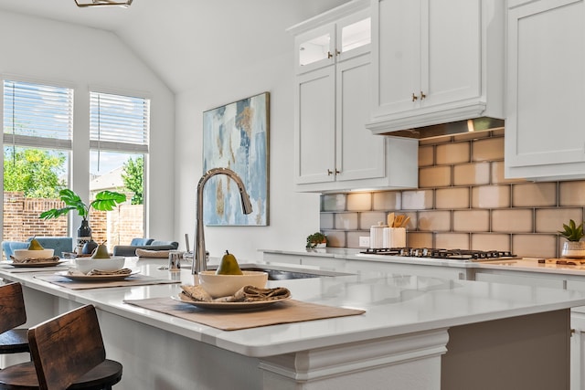 8133 Blumelia Dr, Dallas, TX 75252 - kitchen featuring decorative backsplash, stainless steel gas stovetop, light countertops, a breakfast bar, and white cabinetry