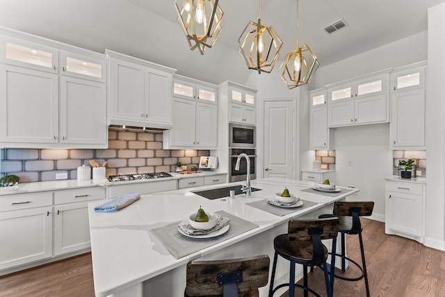 8133 Blumelia Dr, Dallas, TX 75252 - kitchen featuring a chandelier, white cabinetry, a kitchen island with sink, light countertops, and decorative backsplash