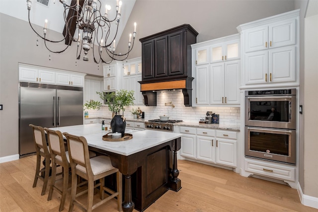 3208 Twin Eagles Dr, Celina, TX 75009 - kitchen featuring stainless steel appliances, a chandelier, light wood-style floors, backsplash, and a high ceiling