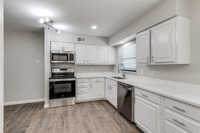 2406 Globe Ave, Dallas, TX 75228 - kitchen with appliances with stainless steel finishes, light wood-style floors, white cabinetry, and recessed lighting