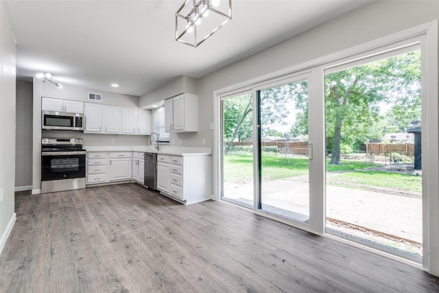 2406 Globe Ave, Dallas, TX 75228 - kitchen featuring stainless steel appliances, light countertops, light wood-style floors, white cabinets, and recessed lighting