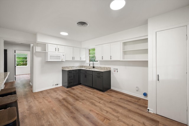2040 Bowie Dr, Corsicana, TX 75110 - kitchen with open shelves, white microwave, gray cabinetry, and healthy amount of natural light