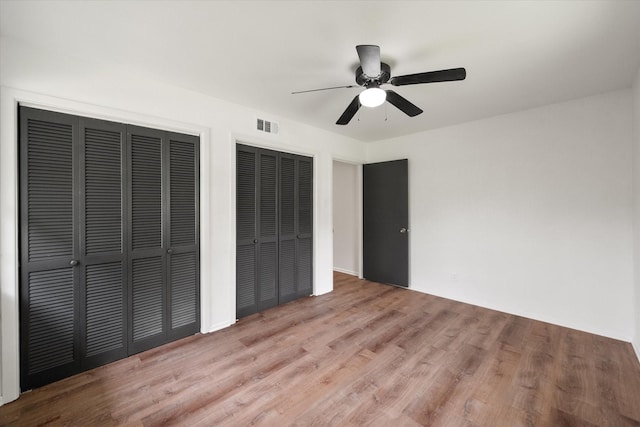 2040 Bowie Dr, Corsicana, TX 75110 - unfurnished bedroom featuring two closets, wood finished floors, and a ceiling fan
