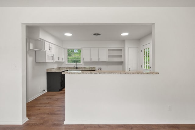 2040 Bowie Dr, Corsicana, TX 75110 - kitchen with open shelves, white cabinets, a peninsula, wood finished floors, and white microwave