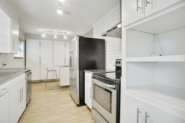 108 Sunnyvale Ter, Hurst, TX 76053 - kitchen featuring appliances with stainless steel finishes, wall chimney range hood, white cabinetry, and decorative backsplash