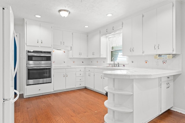 2333 Hermanson Dr, Waco, TX 76710 - kitchen with stainless steel double oven, freestanding refrigerator, open shelves, white cabinetry, and decorative backsplash