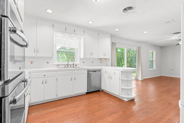 2333 Hermanson Dr, Waco, TX 76710 - kitchen featuring dishwasher, a peninsula, tasteful backsplash, white cabinetry, and open shelves