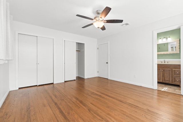 2333 Hermanson Dr, Waco, TX 76710 - unfurnished bedroom featuring two closets, wood finished floors, ensuite bathroom, and ceiling fan