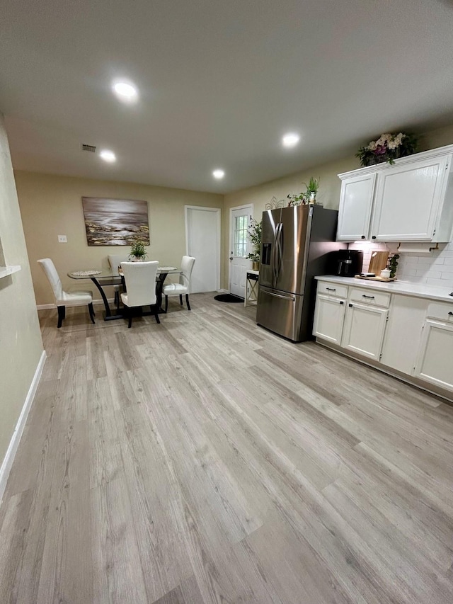 307 E 5th St, Kaufman, TX 75142 - kitchen featuring stainless steel fridge with ice dispenser, light wood finished floors, white cabinetry, recessed lighting, and tasteful backsplash