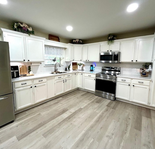 307 E 5th St, Kaufman, TX 75142 - kitchen featuring stainless steel appliances, backsplash, white cabinetry, light wood-type flooring, and light countertops