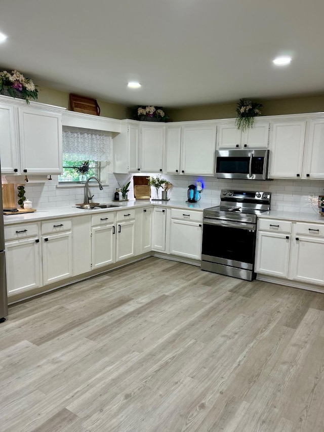 307 E 5th St, Kaufman, TX 75142 - kitchen featuring stainless steel appliances, backsplash, light countertops, white cabinetry, and recessed lighting