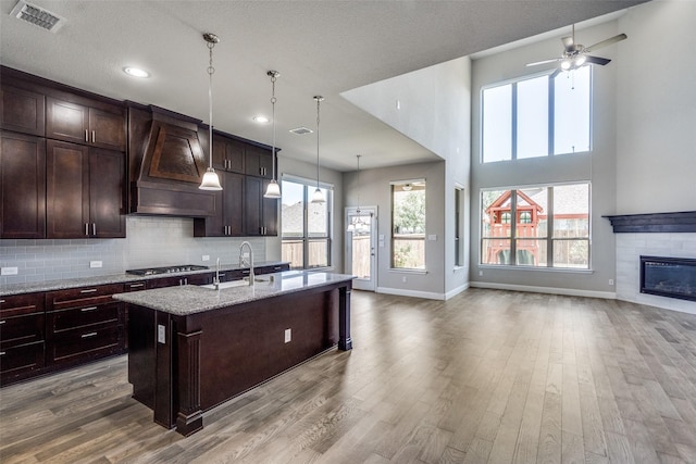6105 Horsetail Dr, Mckinney, TX 75071 - kitchen with custom range hood, open floor plan, a kitchen island with sink, wood finished floors, and recessed lighting