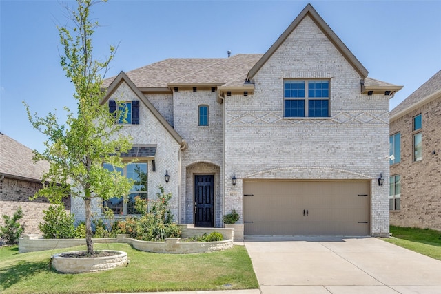 6105 Horsetail Dr, Mckinney, TX 75071 - french country inspired facade with an attached garage, driveway, brick siding, a front lawn, and roof with shingles