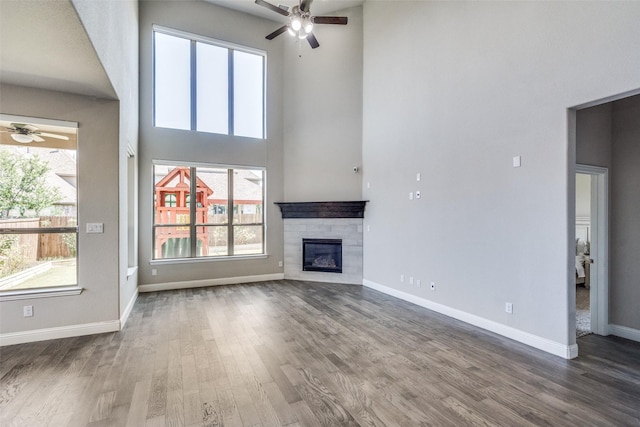 6105 Horsetail Dr, Mckinney, TX 75071 - unfurnished living room featuring a ceiling fan, a high ceiling, wood finished floors, and a glass covered fireplace