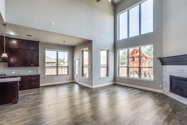 6105 Horsetail Dr, Mckinney, TX 75071 - unfurnished living room featuring a ceiling fan, dark wood-style floors, a high ceiling, and a fireplace