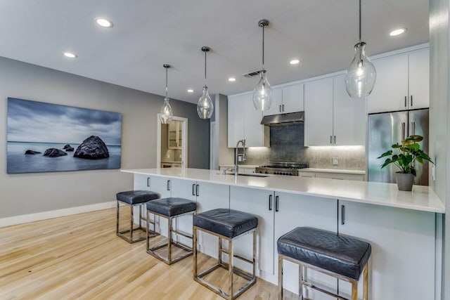 3866 Lively Ln, Dallas, TX 75220 - kitchen with stainless steel refrigerator, decorative backsplash, under cabinet range hood, stove, and a breakfast bar