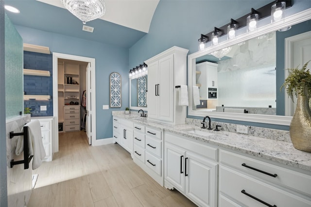 1030 Double B Trl, Prosper, TX 75078 - bathroom with double vanity, a chandelier, a walk in closet, wood finished floors, and lofted ceiling