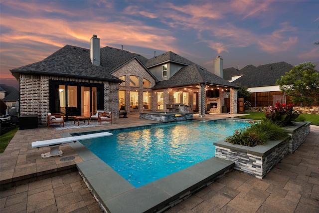 1030 Double B Trl, Prosper, TX 75078 - pool at dusk featuring a patio, outdoor lounge area, a diving board, and a pool with connected hot tub