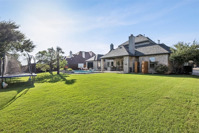 1030 Double B Trl, Prosper, TX 75078 - rear view of house with a trampoline, brick siding, a chimney, roof with shingles, and a patio area