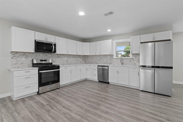 4118 Princeton Dr, Garland, TX 75042 - kitchen featuring stainless steel appliances, light countertops, white cabinets, light wood-style flooring, and recessed lighting