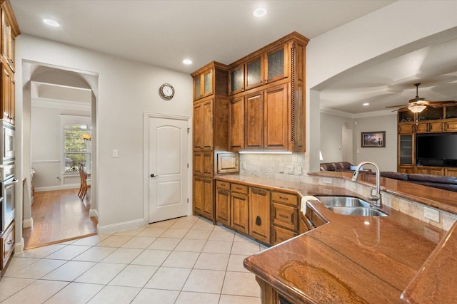 1911 Saddlehorn Ln, Mansfield, TX 76063 - kitchen featuring arched walkways, brown cabinetry, recessed lighting, a ceiling fan, and stone counters