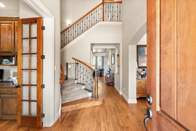 1911 Saddlehorn Ln, Mansfield, TX 76063 - entrance foyer featuring light wood-type flooring, stairs, a high ceiling, and arched walkways