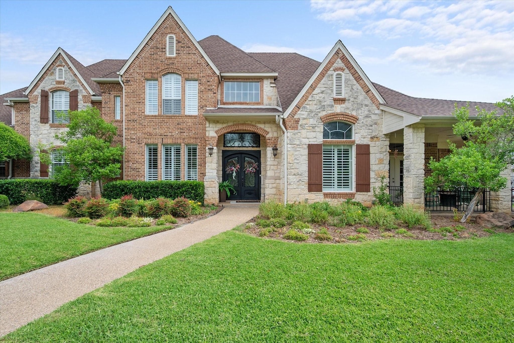 1608 Arborcreek Trl, Mansfield, TX 76063 - view of front of home with french doors, stone siding, a shingled roof, a front lawn, and brick siding