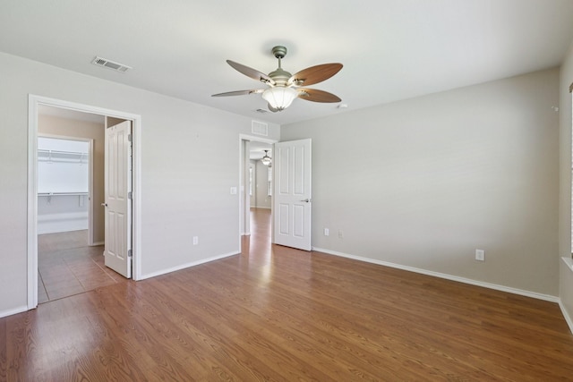 7850 Estancia Dr, Frisco, TX 75036 - unfurnished bedroom featuring wood finished floors, a walk in closet, and a ceiling fan