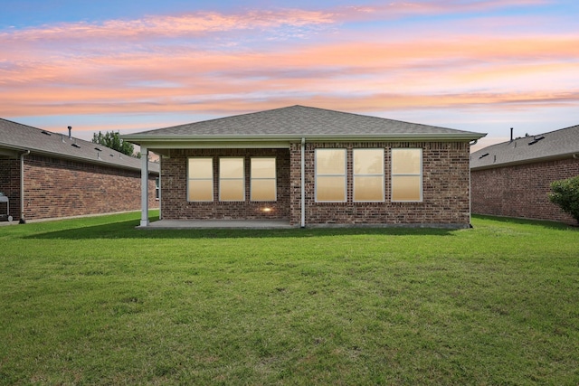 7850 Estancia Dr, Frisco, TX 75036 - back of property at dusk featuring a patio, a lawn, and brick siding