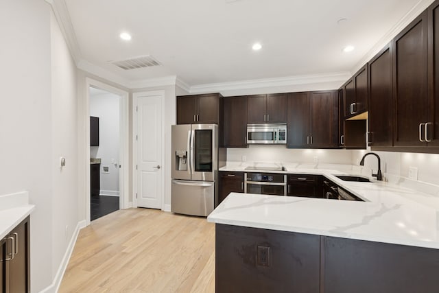 2300 Leonard St Unit 305, Dallas, TX 75201 - kitchen featuring appliances with stainless steel finishes, dark brown cabinetry, light wood-type flooring, ornamental molding, and a peninsula