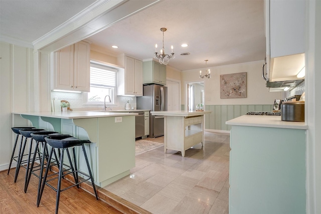 2012 Carleton Ave, Fort Worth, TX 76107 - kitchen featuring ornamental molding, a chandelier, a kitchen bar, stainless steel appliances, and backsplash