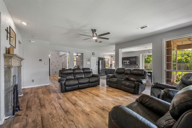 7305 Meadowwood Dr, Rowlett, TX 75089 - living area with wood finished floors, a ceiling fan, a fireplace, and a textured ceiling